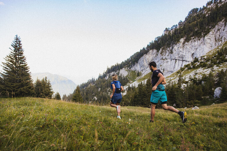 Two trail runner running through a field 